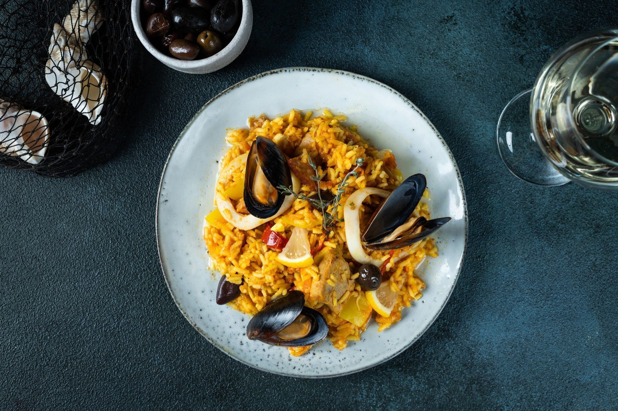 Assiette de paella avec des moules et des crevettes accompagné d'un verre de vin