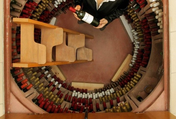 Cave à vin enterrée ronde comprenant des bouteilles de vin et une personne